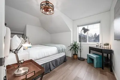 a bedroom with a bed and a desk and a window at Luxurious Retreat/Hot Tub/Mountain View/4 Beds in Canmore