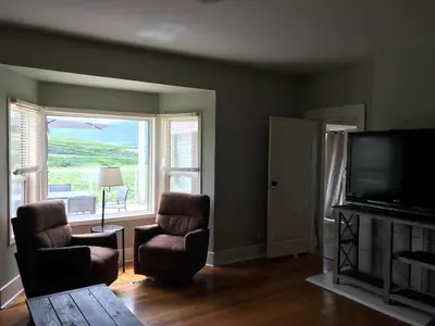 a living room with two chairs and a flat screen tv at D'Angelo Winery Farm House in Penticton