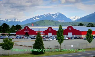 a large red barn with mountains in the background at Spacious 2BR Near HWY 1-Heritage Park - Cultus Lake -Fishing! in Chilliwack