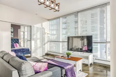 a living room with a couch and a flat screen tv at Luxury 2BR Condo - Downtown City Views in Calgary