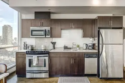 a kitchen with wooden cabinets and stainless steel appliances at Luxury 2BR Condo - Downtown City Views in Calgary