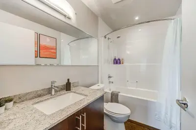 a bathroom with a sink and a toilet and a tub at Luxury 2BR Condo - Downtown City Views in Calgary