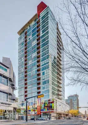 a tall building with glass windows on a city street at Luxury 2BR Condo - Downtown City Views in Calgary