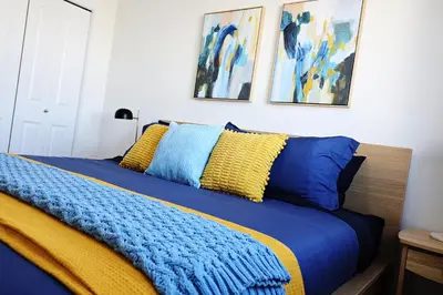 a bed with a blue and yellow blanket and some paintings at BoHo Retreat with King Beds, Golf, Disney+, Near WEM in Edmonton