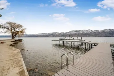 a dock on a lake with mountains in the background at Secluded Cabin On The Lake #7 in West Kelowna
