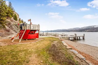 a red boat on the shore of a body of water at Secluded Cabin On The Lake #7 in West Kelowna