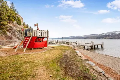 a red boat on the shore of a body of water at Family-friendly Cottage with amazing views in West Kelowna