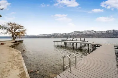 a dock on a lake with mountains in the background at The Lakeside Condo #202 in West Kelowna