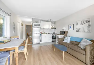 a living room with a couch and a table and a kitchen at The Lakeside Cabin with wide outside space #105 in West Kelowna