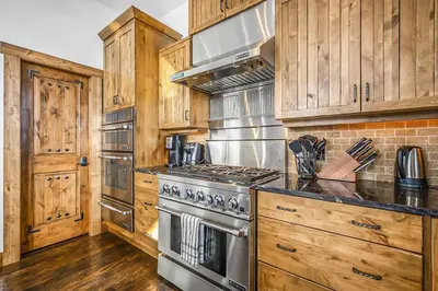 a kitchen with wooden cabinets and a stove top oven at Inuksuk Lodge - 4800 sq ft of Big White Excellence! in Big White