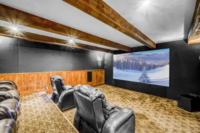 a cinema room with leather chairs and a large screen at Inuksuk Lodge - 4800 sq ft of Big White Excellence! in Big White