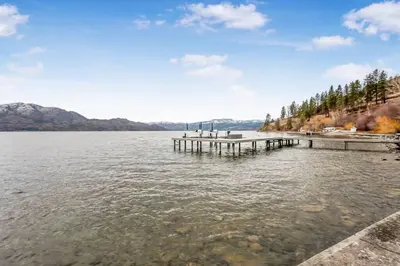 a dock on a lake with mountains in the background at The Perfect Getaway Cabin in the Okanagan #6 in West Kelowna