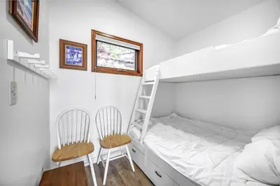 a bedroom with a bunk bed and a ladder and two chairs at Cozy Cottage by the Lakeshore #4 in West Kelowna