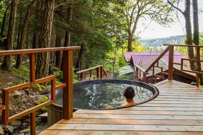 a man in a hot tub on a wooden deck at Sungate on Salt Spring - Luxurious Suite with Cedar Hot Tub & View in Salt Spring Island