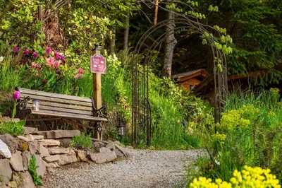 a park bench next to a sign in a garden at Sungate on Salt Spring - Luxurious Suite with Cedar Hot Tub & View in Salt Spring Island