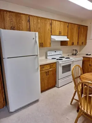 a kitchen with a white refrigerator and a table at 1-Bedroom Basement Suite in Yellowknife