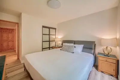 a bedroom with a large white bed and a night stand at Bow Valley Chalets-Entire 2 King Bedrooms townhouse in Canmore