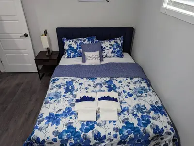 a bed with a blue and white comforter and pillows at The Fruitful Vineyard- A Beautiful 2 Bed Suite in Calgary