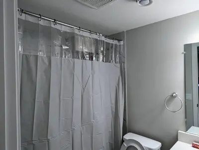 a bathroom with a shower curtain and a toilet at The Fruitful Vineyard- A Beautiful 2 Bed Suite in Calgary