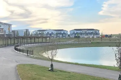 a pond in a park with houses in the background at The Fruitful Vineyard- A Beautiful 2 Bed Suite in Calgary