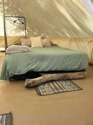 a bed in a tent with a log on the floor at #Y2 Sage & Wildflower Yurt in Drumheller