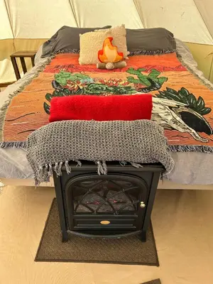 a bed with a fireplace with a blanket on it at #Y5 Lumberjack Lounge Yurt in Drumheller