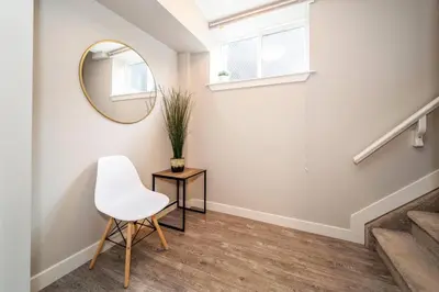 a hallway with a white chair and a mirror at Bright Modern Suite - Netflix - WiFi - Long Stays in Edmonton