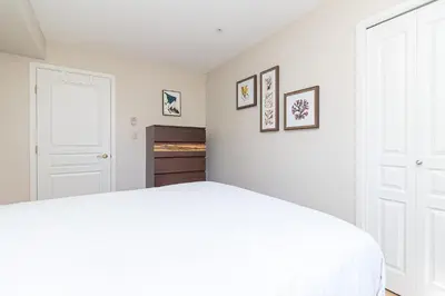 a white bedroom with a white bed and pictures on the wall at Harbour Retreat in Victoria
