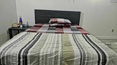 a bed with a striped blanket and two pillows on it at Bright and Cozy Room with Free Parking in Edmonton