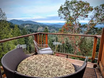 a balcony with two wicker chairs and a table on a deck at Armand Heights in Ganges