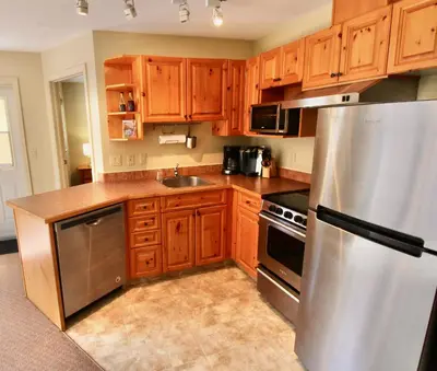 a kitchen with wooden cabinets and a stainless steel refrigerator at Timberline Condos - Aspen Building in Fernie