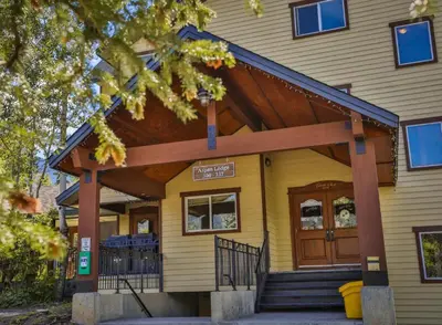 a yellow house with a wooden entrance to it at Timberline Condos - Aspen Building in Fernie