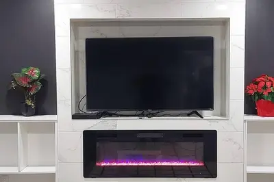 a flat screen tv sitting on a white entertainment center at Cozy 2-Bedroom Basement Guest Suite with Private Entrance and Proximity to the Airport in Edmonton