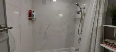 a white bathroom with a shower and a sink at Cozy 2-Bedroom Basement Guest Suite with Private Entrance and Proximity to the Airport in Edmonton