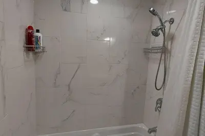a white bathroom with a shower and a tub at Cozy 2-Bedroom Basement Guest Suite with Private Entrance and Proximity to the Airport in Edmonton