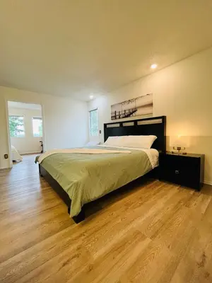 a bedroom with a large bed and a wooden floor at Beautiful home with one acre land for leisure time in Vancouver Island in Nanaimo