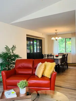 a living room with a red leather couch and a dining room at Beautiful home with one acre land for leisure time in Vancouver Island in Nanaimo