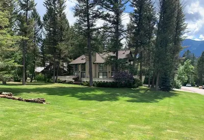 a house in the middle of a yard with trees at Verde Vista - Steam Shower - Theatre - Ping-Pong in Fairmont Hot Springs