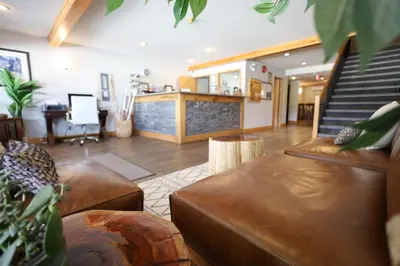a living room with brown leather furniture and a staircase at Glacier Mountain Lodge in Blue River