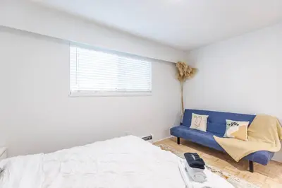 a bedroom with a bed and a blue couch at Beautiful Vancouver Special Home in Vancouver