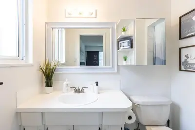 a white bathroom with a sink and a mirror at Beautiful Vancouver Special Home in Vancouver