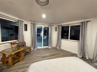 a bedroom with a bed and a table and windows at Cabin in the woods @ Cultus Lake in Chilliwack