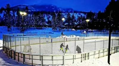 three people are walking around a hockey rink in the snow at Radium 5BR Home Ping Pong, Foosball, & Gazebo in Radium Hot Springs