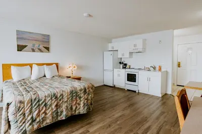 a hotel room with a bed and a kitchen at Western Budget Plus Mosaic Suites in Red Deer