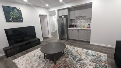 a living room with a table and a refrigerator at Comfy one bedroom Airdrie in Airdrie