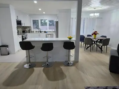 a kitchen and living room with a counter and chairs at 3 Bedroom Home away from Home in Calgary