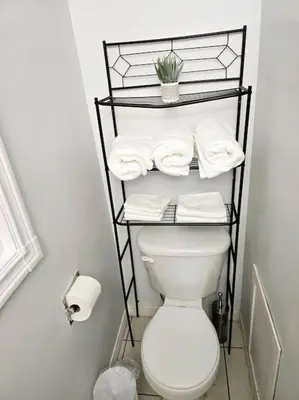 a bathroom with a toilet and a shelf with towels at 3 Bedroom Home away from Home in Calgary