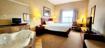 a hotel room with a bed and a bath tub at Park Hill Inn & Suite in Red Deer