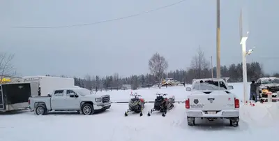 a snow covered parking lot with two horses and trucks at GRIZZLY MOTEL in Swan Hills