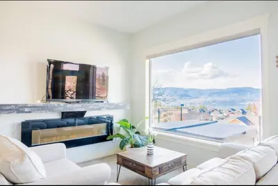 a living room with a fireplace and a large window at Lakeview 2-bed 2-bath Entire Suite near Summerhill Winery in Kelowna